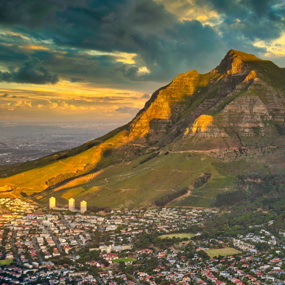 A flat-topped mountain above a coastal city at sunset.
